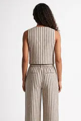 Chaleco beige con rayas verticales oscuras, escote en V y diseño corto sin mangas.