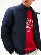 Campera tipo Harrington de Tommy Hilfiger en color azul marino, de corte amplio. Cuenta con cuello alto, cierre frontal de cremallera, bolsillos de ojal en la cintura y el pecho con el logo bordado.