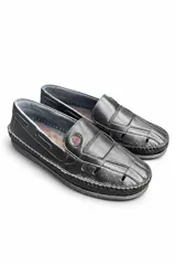 Mocasines de cuero negro con diseño calado, costuras visibles en contraste y suela plana.