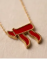 Collar de acero con baño de oro y dije en forma del símbolo Jai esmaltado en rojo, con cadena fina de eslabones.