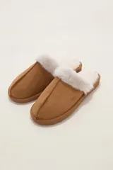 Pantuflas cerradas de color tostado con interior y reborde superior de piel sintética blanca, suela plana y costuras visibles en la parte frontal.