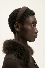 Saco corto de punto fino color marrón oscuro, con cuello de pelo sintético marrón oscuro y cierre frontal de botones metálicos. Posee bolsillos delanteros insertados.