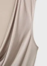 Body sin mangas de color beige, con escote drapeado y diseño entallado. Confeccionado en tejido elástico con tirantes anchos.
