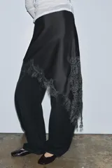 Falda corta de tiro medio confeccionada en tejido satinado negro, con bajo asimétrico y aplicación de encaje a tono.