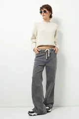 Pantalón de jean negro de corte ancho y tiro alto, con cordón ajustable en la cintura.