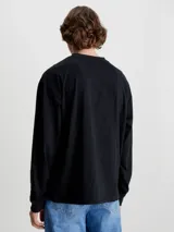 Remera de manga larga Calvin Klein Jeans, color negro, con corte oversized y cuello redondo. Presenta un logo estampado en el centro del pecho sobre una franja horizontal azul.