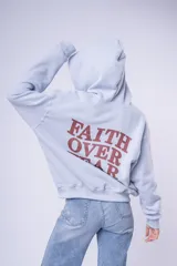 Canguro con capucha color blanco, confeccionado en algodón, con bolsillo frontal tipo canguro y pequeño bordado en el pecho.