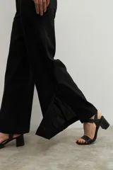 Pantalón negro de lino, de corte ancho y tiro alto, con tajo lateral en el ruedo.