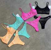 Conjunto de bikini con corpiño tipo top y bombacha tipo tanga, con apliques de strass.