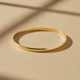 Brazalete tipo esclava rígida de diseño bombé, confeccionado en oro 18k con acabado pulido brillante.