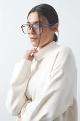 Polera de tejido liviano color negro con cuello alto y silueta relajada. Presenta mangas largas con puños ajustados y recortes laterales que aportan estructura al diseño.