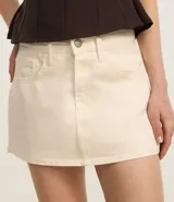 Short pollera de sarga color beige, con diseño de tiro medio, trabillas en la cintura, bolsillos laterales y cierre frontal con botón y cremallera.
