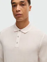 Polo de punto color crema, de corte slim-fit, manga larga y cuello polo con tres botones.