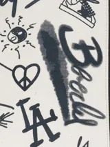 Bolso tipo tote de lona color crudo con estampado de grafitis en negro y asas de cuero negro.