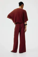 Pantalón de punto bordó de corte holgado con piernas amplias, tiro alto, cintura elástica y cordón ajustable.