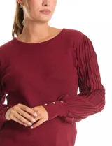 Buzo de tejido lurex marca Nanette, con cuello redondo y mangas largas con diseño plisado. Presenta puños ajustados con aplique de botones decorativos.