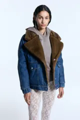 Campera reversible de denim azul con interior de piel sintética marrón. Presenta cuello solapa amplio, cierre frontal con botones metálicos, bolsillos con solapa y puños elásticos.