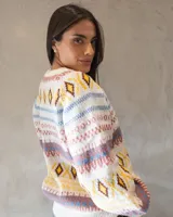 Sweater de tejido de punto con diseño nórdico y geométrico multicolor sobre base color crema. Presenta cuello redondo, mangas largas amplias con puños ajustados y un calce relajado.