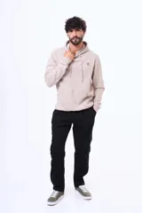 Buzo tipo canguro con capucha y cordones ajustables, confeccionado en felpa color beige. Presenta un pequeño logo bordado en el pecho y una etiqueta decorativa en el puño de la manga.