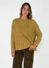 Sweater de punto con diseño de trenzas verticales, cuello redondo y mangas largas. Presenta un corte holgado y cómodo.