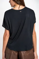 Remera negra de corte oversize, con mangas cortas y cuello redondo, confeccionada en tejido de viscosa y elastano de caída fluida.