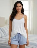 Pijama de dos piezas compuesto por un camisón de breteles finos y un short. El camisón es blanco con un estampado de puntos pequeños y tiene ribetes celestes en el escote en V. El short es celeste liso, de tejido acanalado y con borde ondulado.