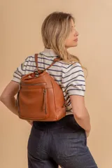 Cartera mochila versátil de cuero sintético con textura granulada, color negro. Cuenta con múltiples bolsillos frontales con cierre, correas ajustables que permiten su uso tanto como cartera de hombro o como mochila, y herrajes metálicos.