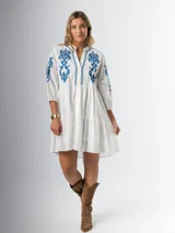 Vestido corto blanco de algodón italiano con bordado azul, mangas tres cuartos y botones frontales. Tiene forro interior en la falda.