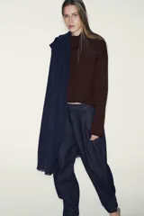 Pantalón de denim azul oscuro, tiro alto, con pinzas delanteras que generan volumen en la cadera y pernera ancha y recta. Presenta cierre frontal y bolsillos laterales.