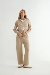 Conjunto de dos piezas de tejido de punto color beige, compuesto por una campera con cierre frontal y cuello alto, y un pantalón de corte recto y tiro alto con cintura elástica.