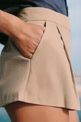 Shorts de tiro medio con bolsillos laterales y detalle de pinzas delanteras. Cierre frontal con cremallera, botón interior y gancho metálico.