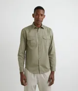 Camisa verde militar de manga larga en sarga de algodón, con cuello clásico, cierre frontal abotonado y dos bolsillos con solapa abotonada en el pecho.