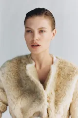 Abrigo de Zara Woman Collection con textura efecto pelo, cuello redondo y manga larga. Presenta un diseño cruzado con cinturón ajustable del mismo tejido y bolsillos delanteros.