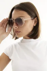Lentes de sol con armazón de policarbonato negro y cristales tonalidad ámbar, con diseño de puente doble estilo aviador.
