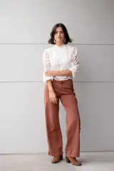 Pantalón de jean color ladrillo, de corte recto y tiro alto, con aberturas laterales en el ruedo y detalle de botones.