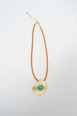 Collar con cordón naranja y dije metálico dorado de forma irregular con piedra central turquesa.