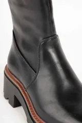 Bota corta de cuero sintético color marrón, con punta redonda, cierre lateral y suela tipo tractor de 6 cm.