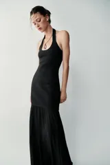 Vestido largo negro de cuello halter, espalda descubierta y escote redondo. Presenta un diseño de punto combinado en la parte superior y una falda larga de tejido fluido.