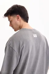 Remera oversize gris oscuro con efecto lavado, cuello redondo y mangas cortas amplias.