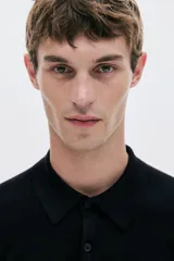 Remera polo de manga larga en punto fino negro, con cuello clásico y tapeta de tres botones. Presenta remates acanalados en puños y bajo.