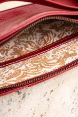 Bandolera roja con estampado de piel de serpiente, correa de cuero y correa de cadena dorada.