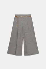 Bermuda larga de tiro alto con diseño de estampado a cuadros tipo pata de gallo. Presenta pinzas delanteras, corte amplio y un cinturón integrado que combina una tira de cuero sintético con una cadena metálica dorada. Cierre lateral con cremallera oculta.
