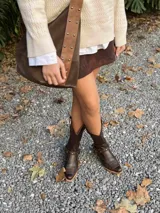 Botas de cuero color chocolate, de caña alta con detalle de hebillas y tachas.