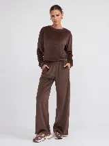 Pantalón de corte recto confeccionado en tejido plush con acabado aterciopelado. Presenta cintura elástica, bolsillos laterales y un bolsillo trasero, ofreciendo una caída fluida y cómoda.