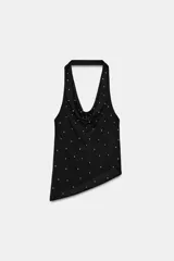Top halter negro con escote drapeado tipo cascada y espalda descubierta. La prenda está adornada con pequeños apliques brillantes distribuidos por toda la tela y presenta un bajo asimétrico.