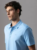 Chomba de manga corta Calvin Klein confeccionada en algodón interlock, con cuello clásico y cierre frontal de botones. Presenta un diseño liso en color celeste con el logo de la marca bordado sutilmente en el pecho.