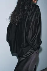 Camisa fluida de cuello redondo con escote en pico y lazada frontal en el mismo tejido. Presenta mangas largas con puños anchos y bajo recto.