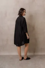 Camisola blanca de silueta amplia y caída liviana, con diseño clásico de cuello camisero, cierre frontal con botones y mangas tres cuartos, decorada con grandes motivos florales bordados.