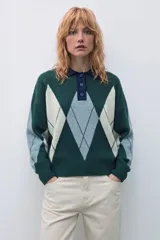 Sweater de tejido de punto con diseño de rombos en tonos verde inglés, gris y beige. Presenta cuello polo con cierre de botones, mangas largas y corte holgado.
