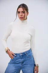 Polerita de cuello alto color crudo, de manga larga y tejido acanalado.